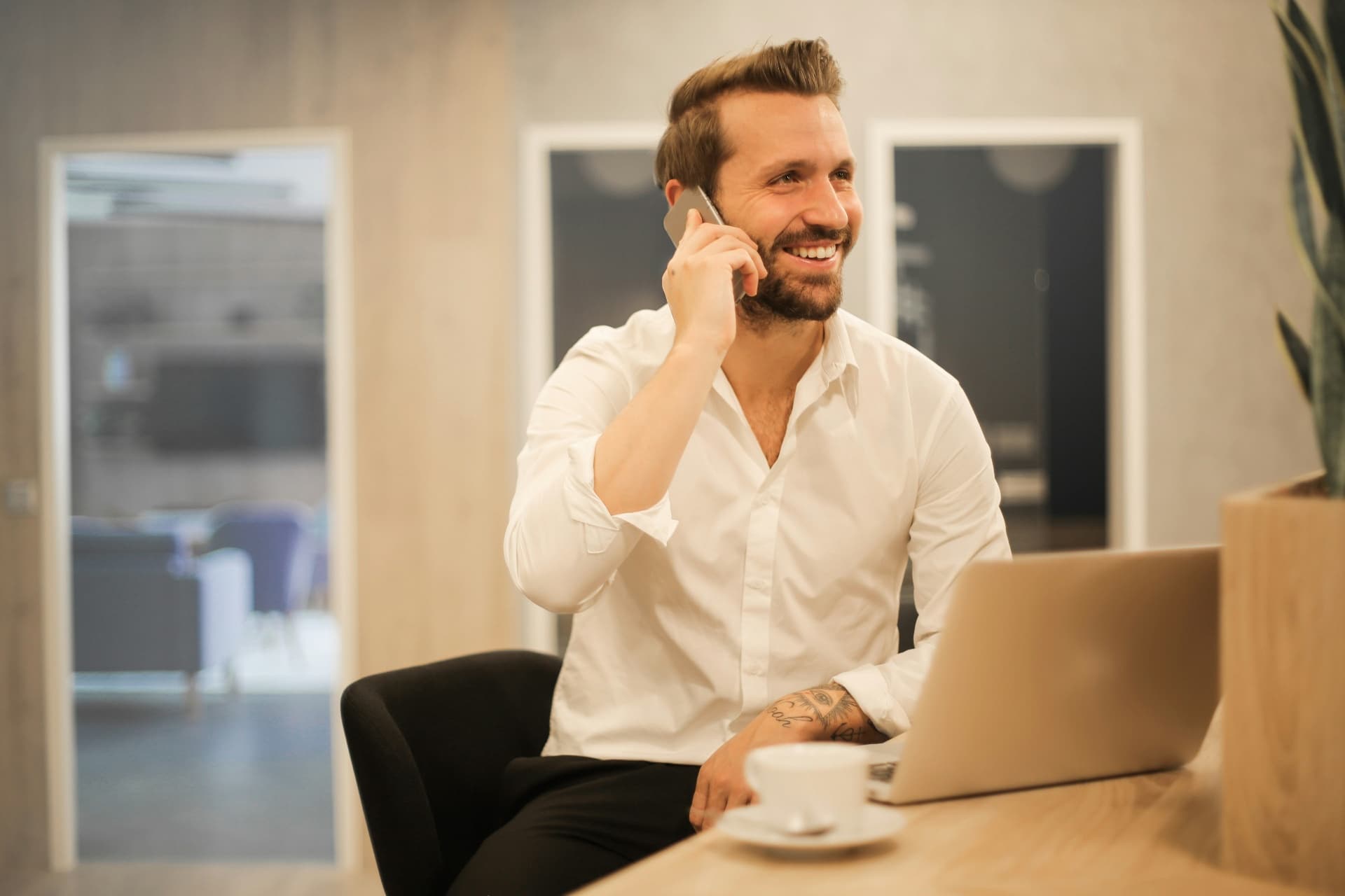 Manager souriant au téléphone devant son ordinateur portable